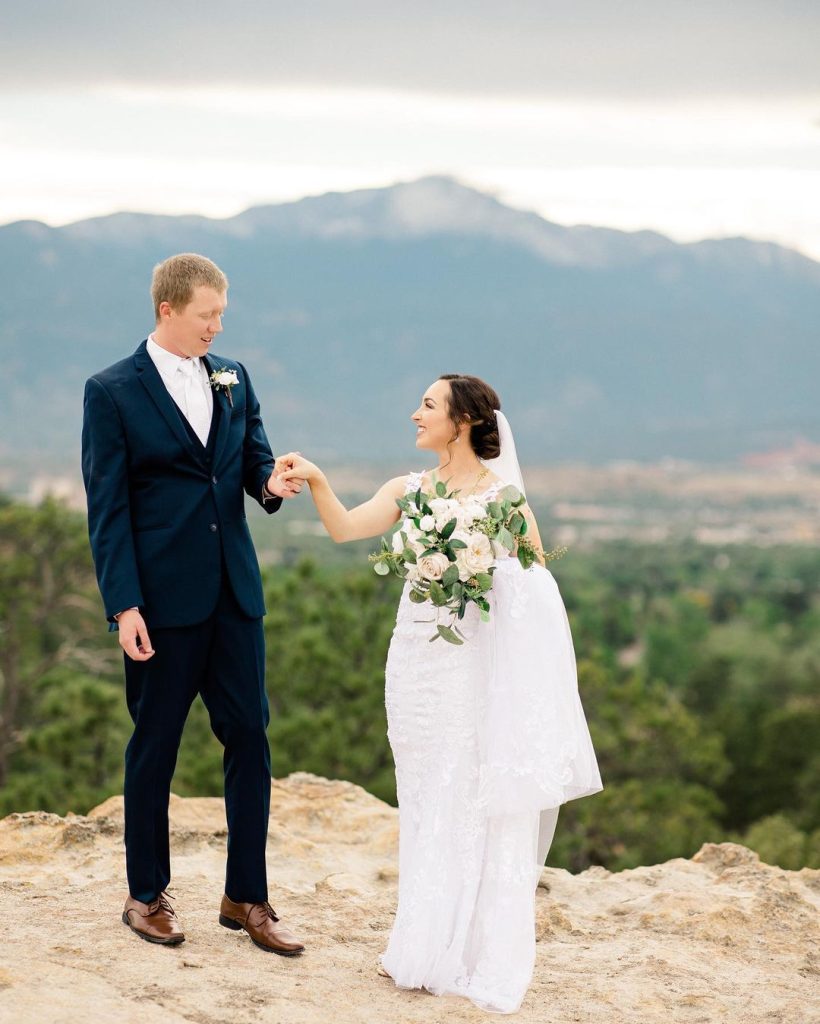 wedding couple during cocktail hour taking portraits with mountains in the background near the venue 820x1024